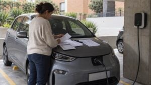 Compradores conversan con una asesora junto a un carro eléctrico en un concesionario genérico
