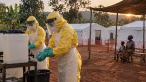 Personal sanitario lava sus guantes frente a carpas mientras una familia espera bajo un toldo