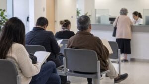 Personas adultas esperan con documentos en una sala de atención de salud en Bogotá.
