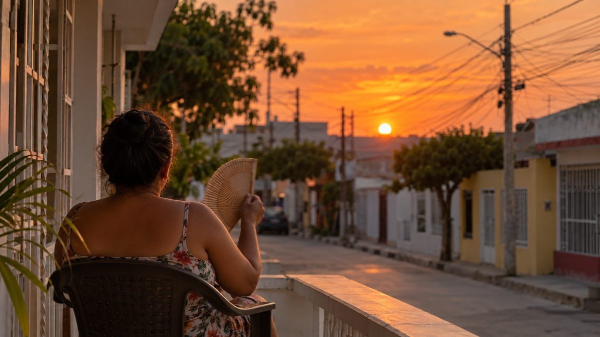 Hacienda giró $300.000 millones al fondo que sostiene a Air-e: los usuarios del Caribe reciben el primer pago de $1,5 billones 1 Mujer sentada en una terraza de barrio al atardecer, entre postes y cables eléctricos