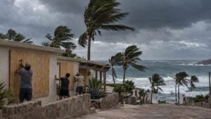 Adultos aseguran embarcaciones en un puerto genérico del Pacífico ante el oleaje y un cielo de tormenta.