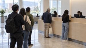 Dos asesoras atienden a clientes adultos mientras otras personas esperan en una sucursal bancaria.