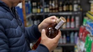 Persona revisa el sello y la tapa de una botella en una licorera genérica