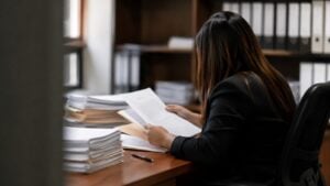 Funcionaria judicial revisa un expediente en papel sobre el escritorio de un despacho.