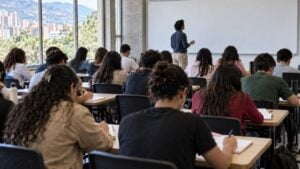 estudiantes en un aula universitaria colombiana con un profesor al frente
