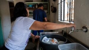Persona cierra la llave mientras lava la loza con cuidado en una cocina sencilla de Medellín.