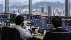 Dos operadores trabajan frente a pantallas en la mesa de dinero de un banco en Bogotá.