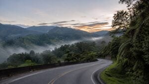 Carretera colombiana de montaña con curvas y niebla al amanecer