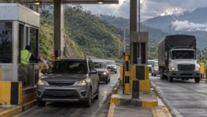 Conductores esperan en una estación de peaje de montaña mientras un operario entrega un recibo