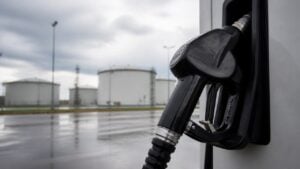Boquilla de combustible frente a tanques de almacenamiento bajo un cielo nublado