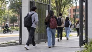 Estudiantes entran a un campus público mientras una motocicleta de patrulla permanece afuera