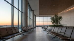 Sala de espera de aeropuerto vacía al amanecer, iluminada por luz suave a través de amplios ventanales