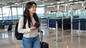 Viajera sostiene su pasaporte junto a una maleta en un aeropuerto