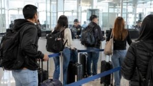 Viajeros colombianos con equipaje frente a un control migratorio en un aeropuerto