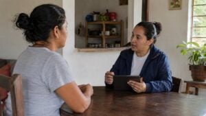 Encuestadora conversa con una persona adulta en una vivienda sencilla de Colombia