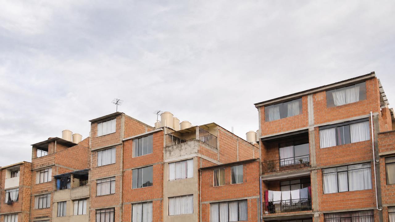La Secretaría del Hábitat abre 527 subsidios de arriendo en Bogotá: los hogares reciben hasta $1.085.561 al mes por seis meses 1 Edificios residenciales de ladrillo con tanques de agua en las azoteas en Bogotá