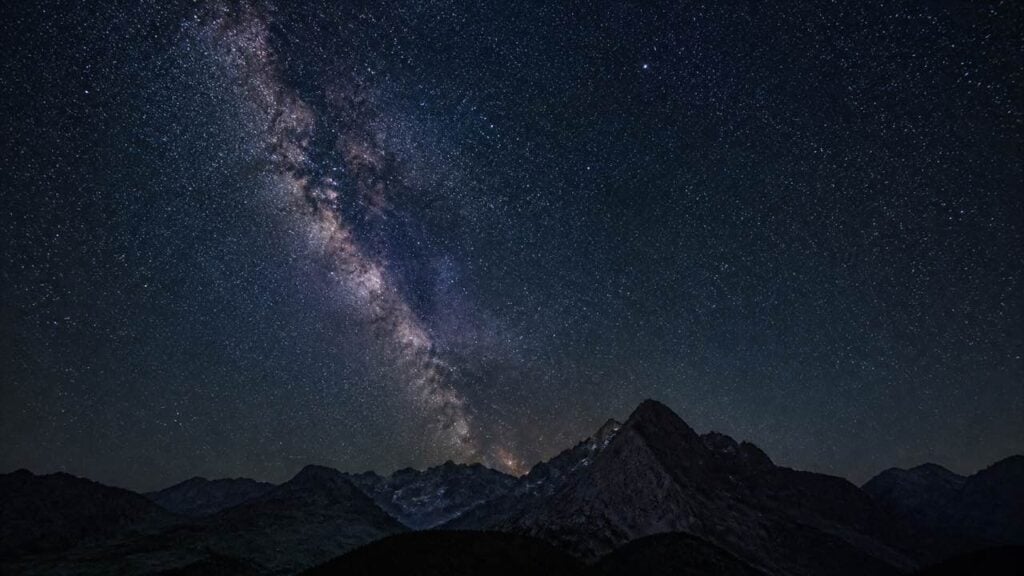 Cielo nocturno estrellado con la Vía Láctea sobre la silueta de montañas