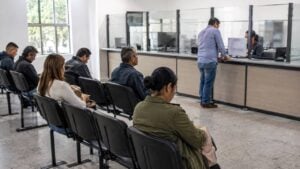 Ciudadanos esperan su turno mientras una persona es atendida en una oficina de trámites