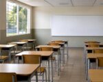 Aula vacía de colegio público con pupitres ordenados y luz natural
