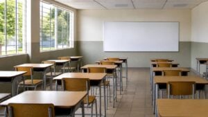 Aula vacía de colegio público con pupitres ordenados y luz natural