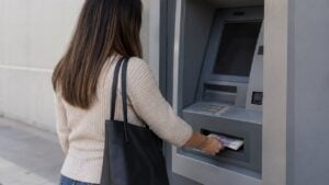 Una mujer retira dinero de un cajero automático en una calle de una ciudad colombiana.