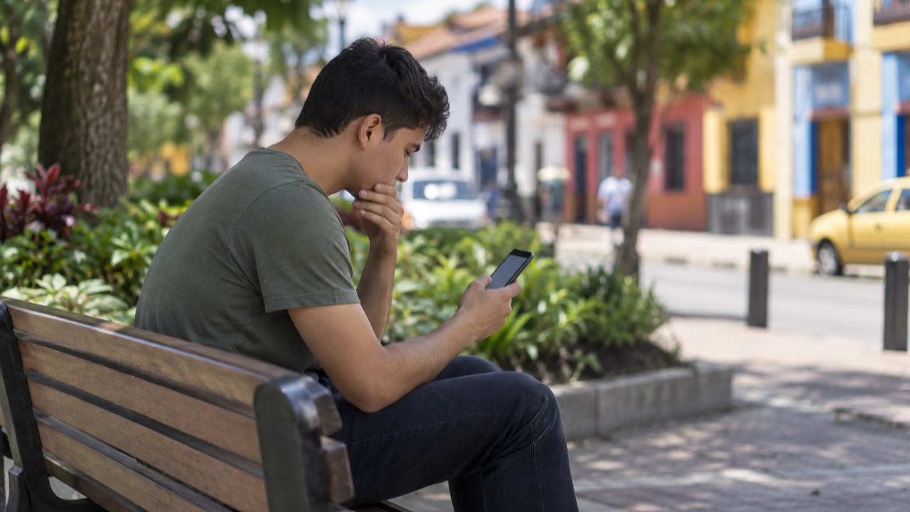 La CRC reportó ante la SIC a Claro, Tigo, Movistar, WOM y ETB: los usuarios hallan en carruseles y menús el canal para cancelar 1 Un hombre joven revisa su celular sentado en la banca de un parque.