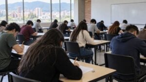 Estudiantes universitarios presentan un examen escrito con lápiz en un salón de clases.