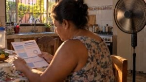 mujer revisa una factura de energía junto a un ventilador en una casa del Caribe colombiano.