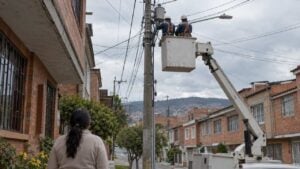 Dos técnicos trabajan en redes eléctricas sobre una canasta elevada en una calle residencial de Bogotá.
