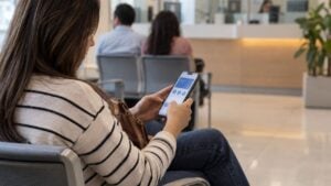 Una mujer revisa su celular en la sala de espera de una oficina bancaria.