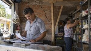 Dueño de un local revisa papeles junto a una pared agrietada y un techo apuntalado