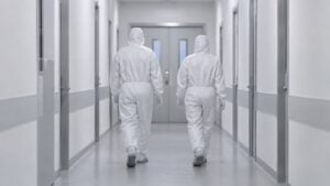 Trabajadores de salud con trajes de protección caminan por el pasillo de un centro de aislamiento.