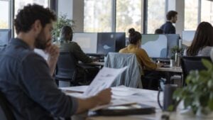 Ingenieros trabajan en una oficina de tecnología mientras uno revisa documentos.