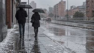 personas caminan por una calle de Bogotá cubierta de granizo.