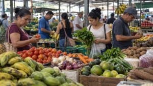 Personas adultas observan productos y comparan precios en una plaza de mercado colombiana genérica.