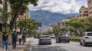 Peatones caminan de espaldas por una avenida de Caracas con el Ávila al fondo.