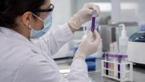 Una bacterióloga examina un tubo de ensayo con un líquido violeta en un laboratorio clínico.