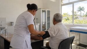 Una enfermera toma la presión a un adulto mayor en un centro de salud durante un día caluroso.