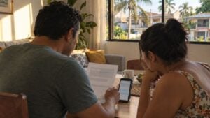 Una pareja revisa una factura y un celular en la sala de su casa en Cali.