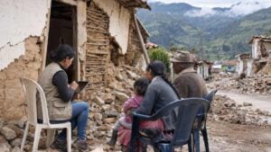Una funcionaria toma los datos de una familia frente a su casa agrietada por el terremoto en un pueblo de montaña.