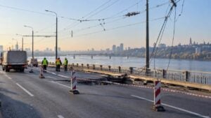 Trabajadores de emergencia revisan la calzada dañada de un puente sobre un río.