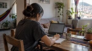 Una joven estudia frente a un portátil en su casa.