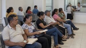 Usuarios esperan sentados en la sala de una sede de EPS mientras atienden una ventanilla