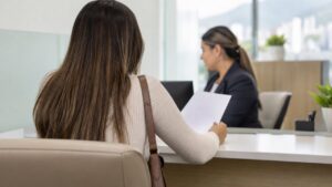 Dos clientes conversan con una asesora en la sucursal de un banco.