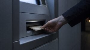 Una mano retira billetes de un cajero automático de noche.