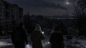 Edificios a oscuras durante un corte de luz y humo de una central eléctrica al fondo.