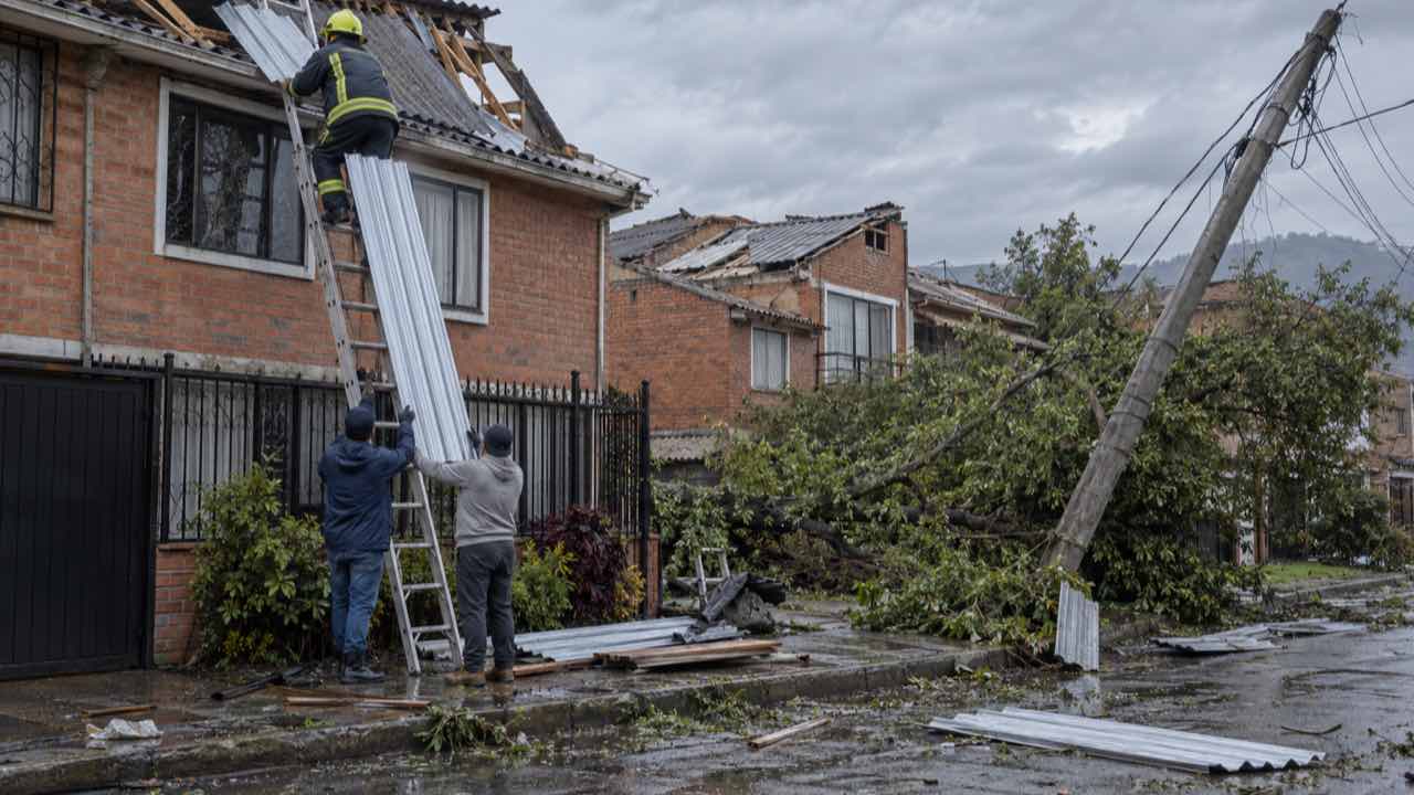 La Gobernación de Cundinamarca reporta más de 300 casas de Funza con daños por el vendaval: en Soacha, la lluvia dejó un muerto 1 Vecinos y un bombero recogen tejas y escombros junto a un árbol caído en una calle de casas de ladrillo en la Sabana de Bogotá.
